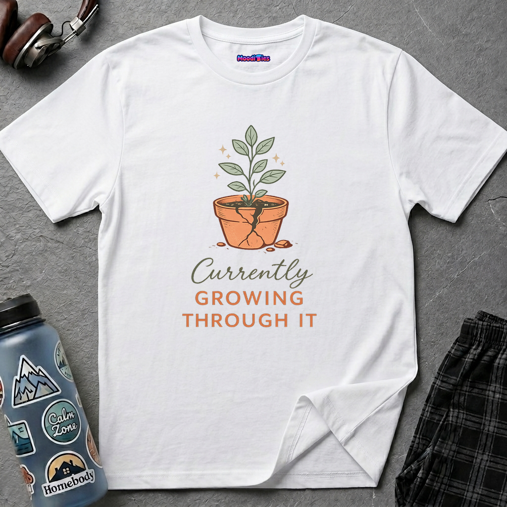 Text "Currently Growing Through It" with green plant growing in a broken terra cotta pot.